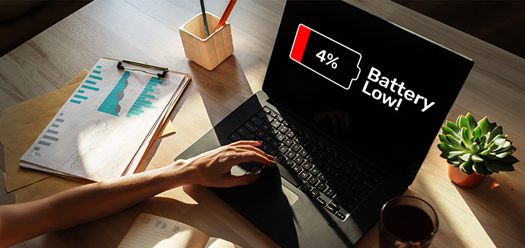 A laptop computer on a table showing a charging bar at low battery